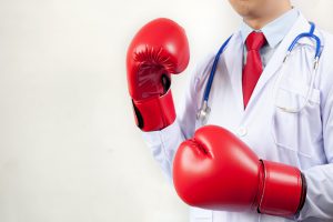 Doctor wearing boxing gloves in white background