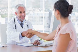 Doctor shaking hands to patient in the office at desk